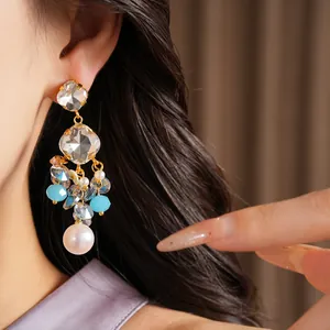 Detail view of gold-tone tassel earrings featuring faceted crystals and blue beads