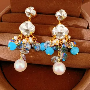 Close-up detail of luxurious vintage-style tassel earrings with crystal stones and pearls.