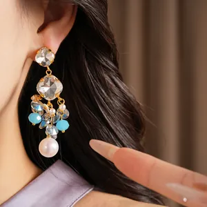 Macro view of vintage geometric crystal tassel earrings featuring a delicate white pearl
