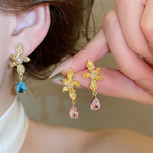 Detail view of 18k gold plated flower earrings with blue and pink teardrop zircons.