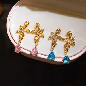 Detail shot of gold floral earrings with pink and blue teardrop stones in a box