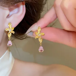 Detailed macro view of 18k gold plated flower stud earring with pink teardrop zircon dangle