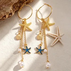 Détail de boucles d'oreilles bohèmes avec étoiles de mer et coquillages dorés et perles