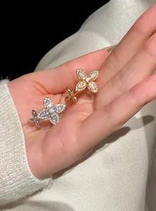 Detail of zircon flower star open rings in silver and rose gold finishes shown on a hand.
