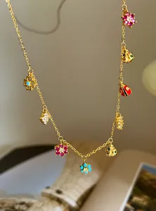 Detailed macro view of a gold-plated necklace featuring vibrant flower and ladybug charms