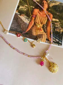 Detail of sweet floral and ladybug charms on gold chain and purple beaded necklace