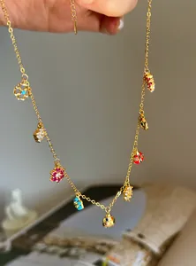 Detail of gold flower charm necklace with colorful ladybug and floral pendants