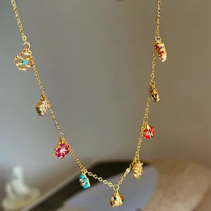 Detailed close-up of a golden clavicle chain necklace with colorful flower and ladybug charms