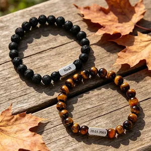 Custom lava stone and tiger eye beaded bracelets set with engraved names on wood background