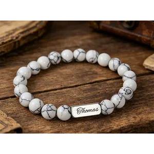 Macro view of white turquoise beads and personalized engraved metal bar with Thomas