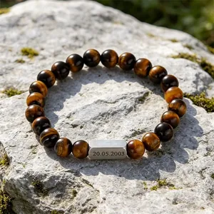 Macro detail of custom engraved metal plate on tiger eye stone beaded bracelet
