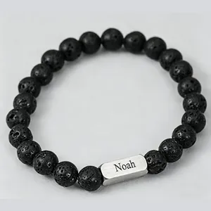 Macro shot of lava stone beaded bracelet with engraved silver Noah metal plate detail
