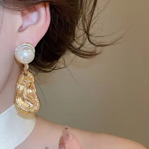 Oversized gold ear-shaped drop earrings with pearl stud for a unique statement look