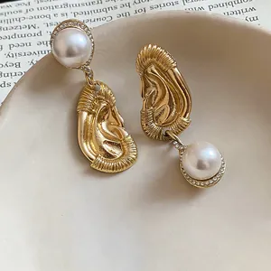 Close-up detail of unique gold-tone ear-shaped drop earrings with white pearls