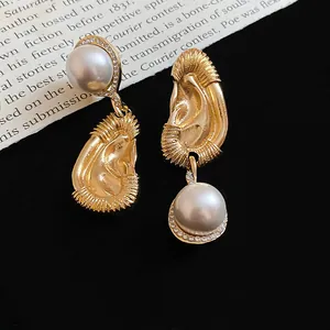 Artistic gold ear-shaped earrings with large round pearl drops and sparkling rhinestones