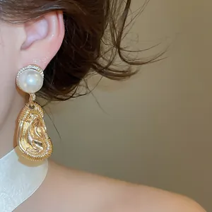 Detail of vintage gold ear-shaped drop earrings featuring a large white pearl bead