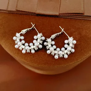 Close-up of silver-tone hoop earrings with white pearls and sparkling cubic zirconia.
