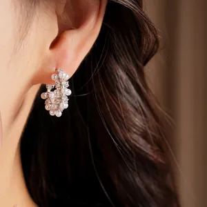 Detail shot of silver hoop earrings adorned with petite pearls and sparkling zircons