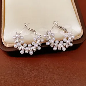 Close-up detail of silver needle earrings with cluster pearls and cubic zirconia stones