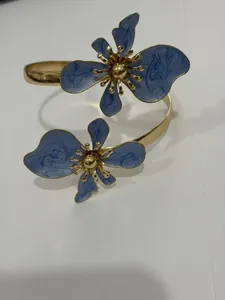 Detailansicht der unregelmäßigen Goldmanschette mit zwei 3D-blauen Emaille-Blumen