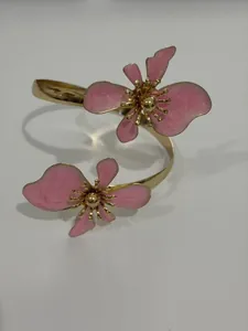 Detail eines goldenen Armreifs mit zwei asymmetrischen rosa Emaille-Blumen-Motiven