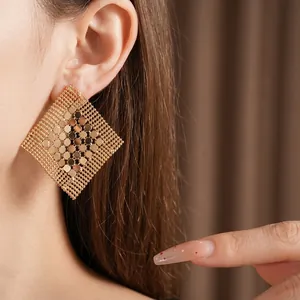 Eleganti orecchini geometrici a rombo in maglia dorata indossati da una modella