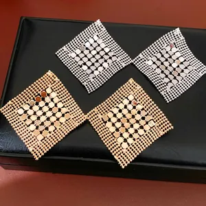 Vue détaillée des boucles d'oreilles géométriques évidées en losange, or et argent