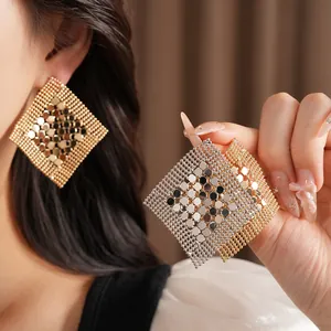 Détail de boucles d'oreilles géométriques en maille losange évidée en or et argent