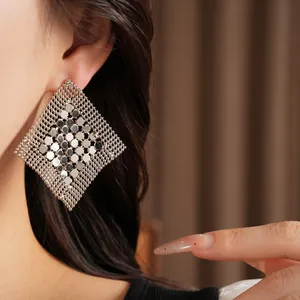 Élégantes boucles d'oreilles clous géométriques en maille losange argentée sur modèle