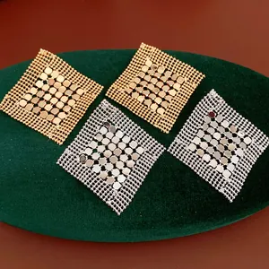 Gros plan de boucles d'oreilles losanges géométriques dorées et argentées sur velours