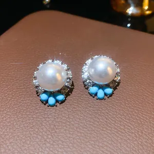 Vista dettagliata di eleganti orecchini a perno con perle bianche, strass e perline blu.