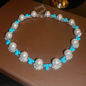 Dettaglio di collana di perle vintage con petali in resina blu e strass brillanti luccicanti