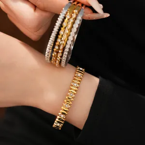 Detailed macro view of elegant gold and silver stainless steel zircon bangles on wrist.