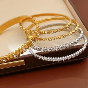 Close-up of stainless steel bangles with cubic zirconia heart and star patterns in a box.