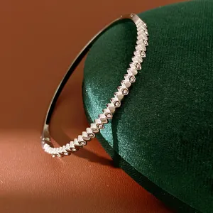 Close-up of a silver stainless steel bangle with zircon heart-shaped link details