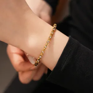 Close-up of a delicate stainless steel gold bracelet with inlaid zircon stars and circles