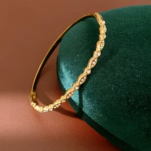 Detailed macro view of a gold wavy stainless steel bangle featuring sparkling zircon stones