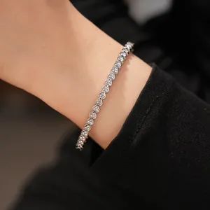 Close-up of silver stainless steel heart-shaped bracelet with zircons on wrist