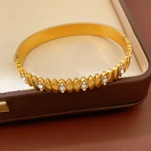 Close-up of gold-plated stainless steel bangle with zircon-embedded oval patterns