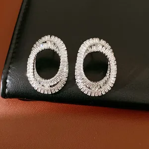 Close-up of elegant oval crisscross stud earrings with sparkling baguette zircons