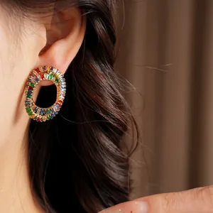 Close-up detail showing colorful baguette zircon oval cross stud earrings on ear.
