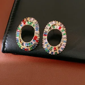 Close-up detail of luxury multi-color zircon oval stud earrings on black leather