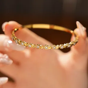Macro view of gold stainless steel bangle featuring inlaid round zircons and star patterns