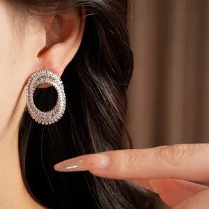 Detail shot of elegant zircon-inlaid oval crossed stud earrings with shimmering finish