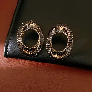 Close-up of elegant oval stud earrings with black baguette-cut zircons and gold plating.