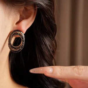 Close-up of elegant gold-toned oval earrings with black rhinestone inlay on model