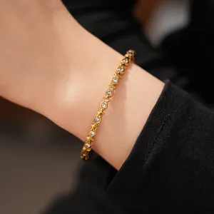 Detail shot of a gold stainless steel bracelet with star and zircon accents on a wrist