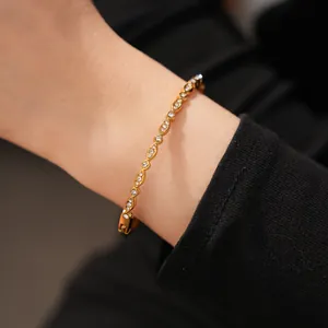 Detail view of gold-plated stainless steel bracelet with zircon stones on wrist.
