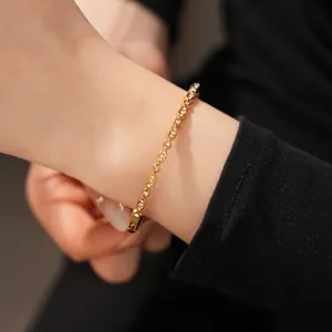 Close-up of elegant gold zircon bracelet on wrist with sparkling oval links design.