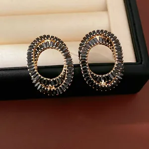 Detail shot of oval cross-over stud earrings featuring black baguette zircons